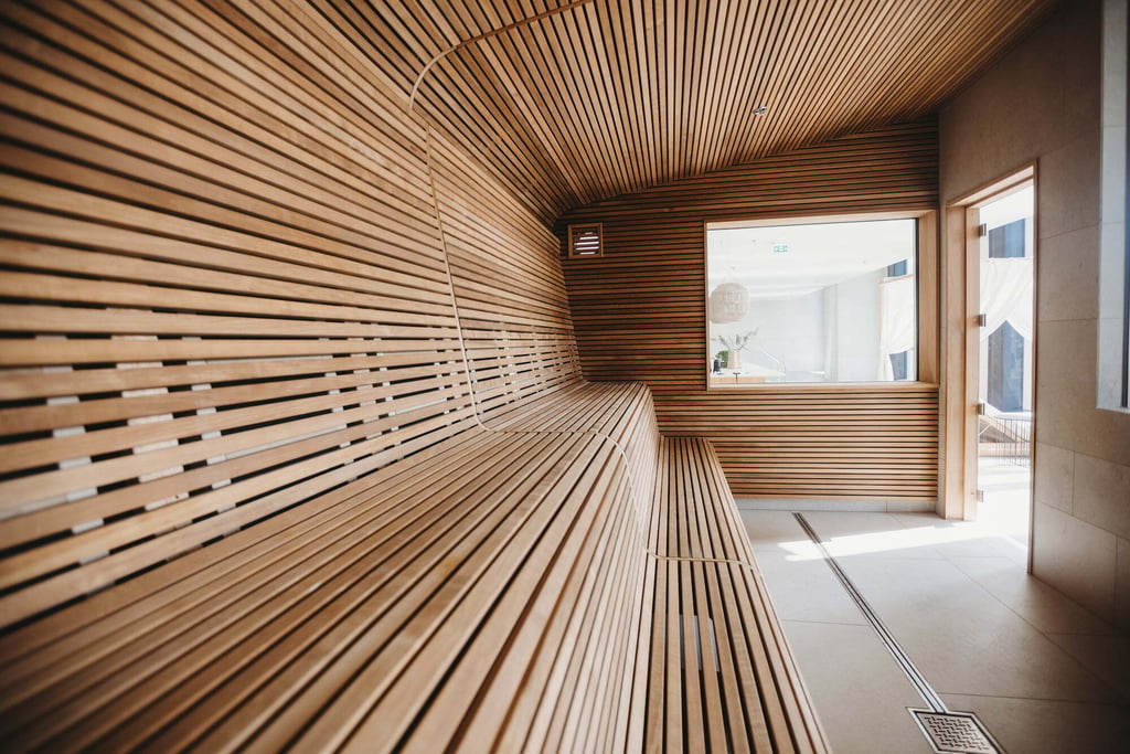 Modernes Sauna-Interieur mit geriffelter Holzverkleidung, integrierter Beleuchtung und sorgfältig geplanter Bankanordnung.